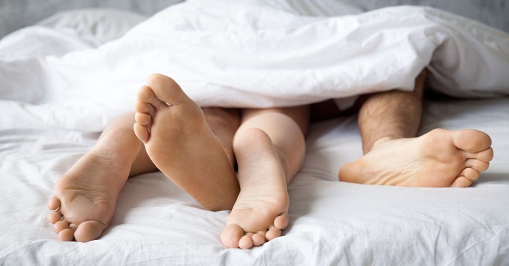 Couple with legs intertwined under sheets - improved libido after work at Eastwest Integrated Care and the use of Traditional Chinese Medicine